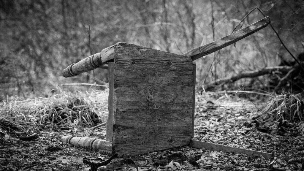 Pied de meuble ancien en bois, vu de près, avec des trous circulaires